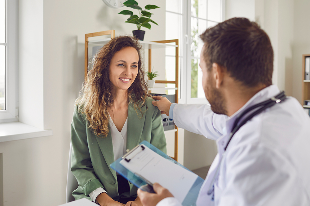 médico sorridente apoiando paciente durante atendimento humanizado