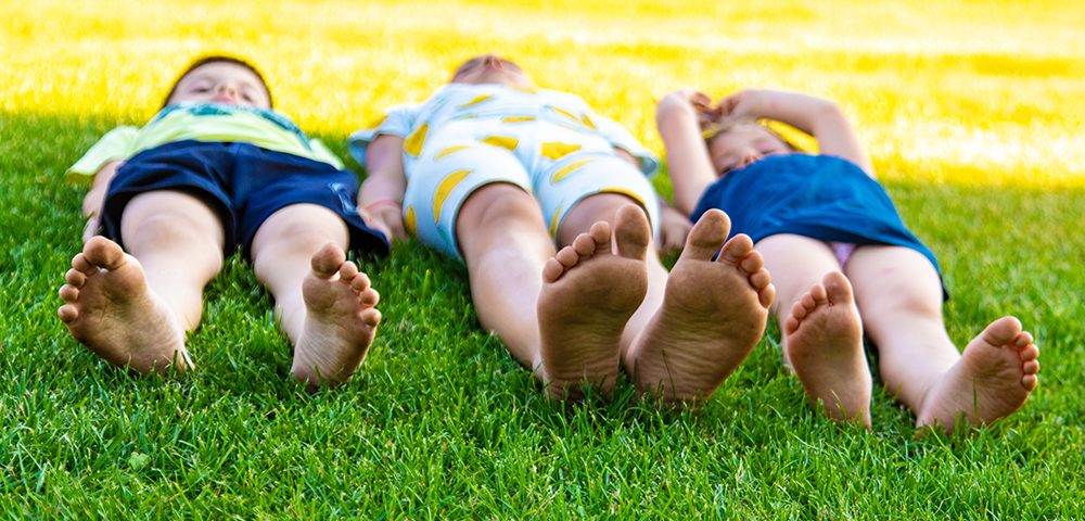crianças deitadas na grama aproveitando um dia ensolarado ao ar livre