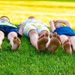 crianças deitadas na grama aproveitando um dia ensolarado ao ar livre