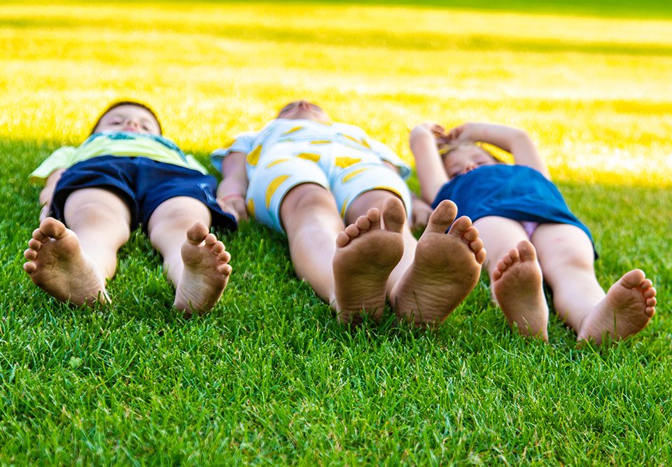 crianças deitadas na grama aproveitando um dia ensolarado ao ar livre