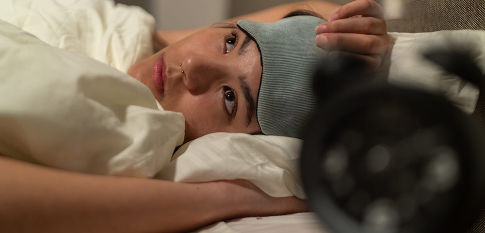 Jovem estressada sofrendo de insônia deitada na cama à noite