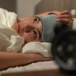 Jovem estressada sofrendo de insônia deitada na cama à noite