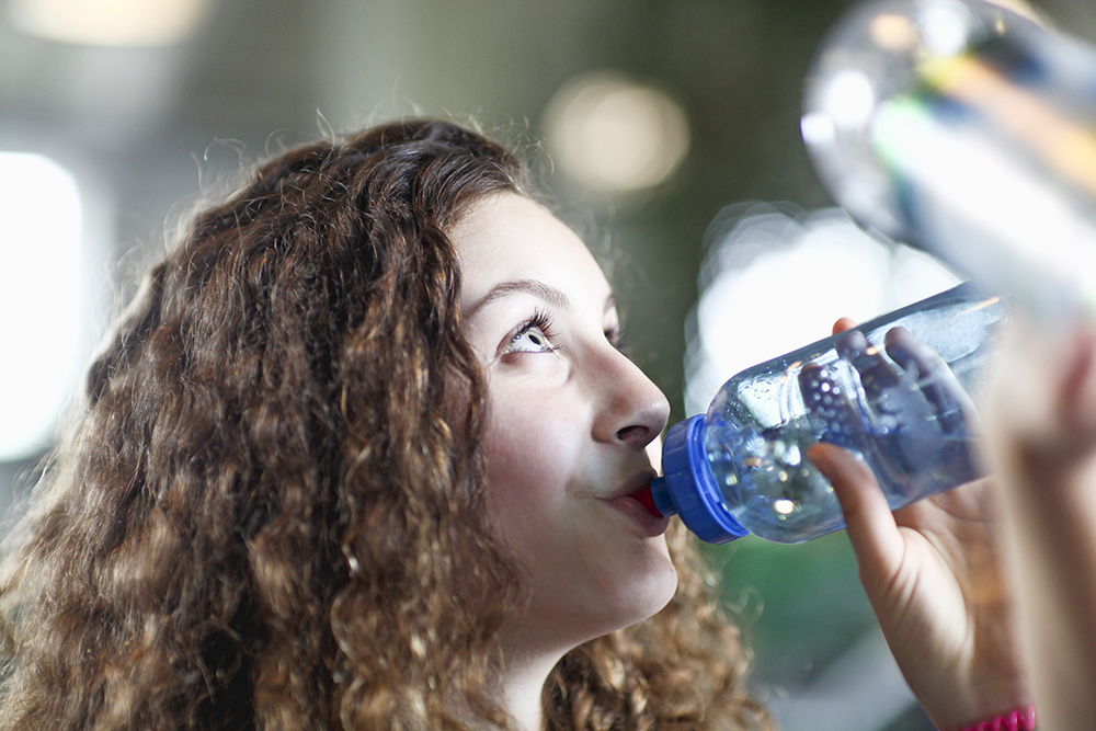 mulher se hidratando durante onda de calor para evitar desidratação