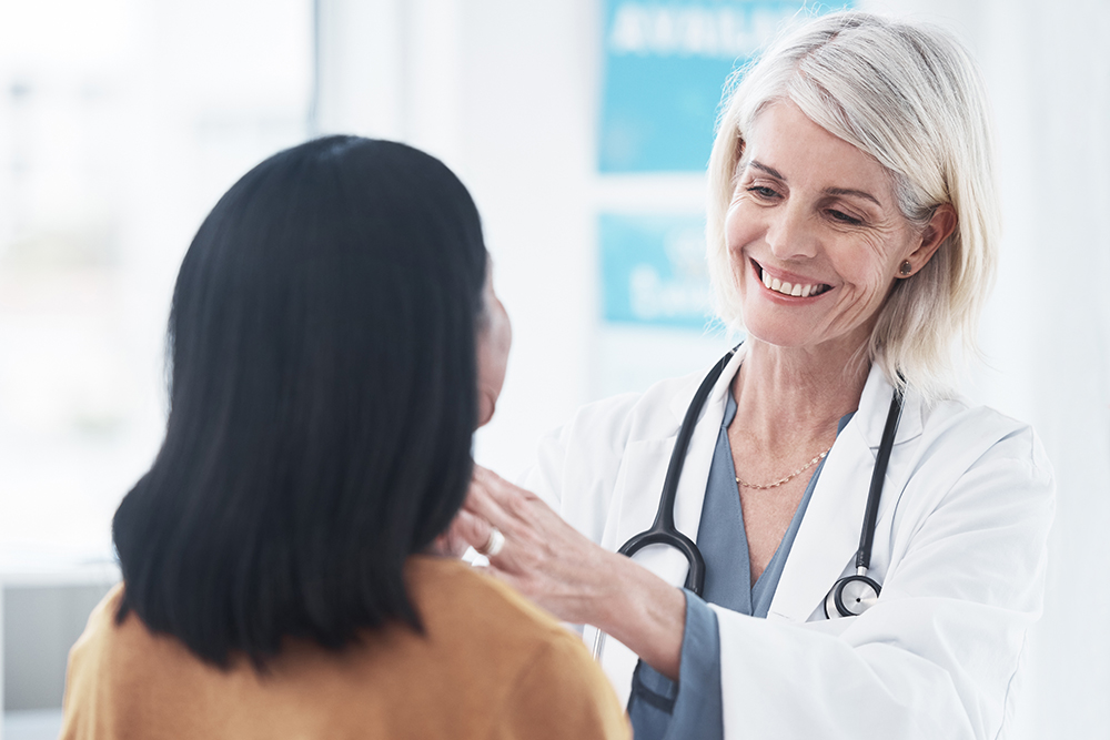 Uma médica examinando a garganta de uma mulher durante uma consulta.