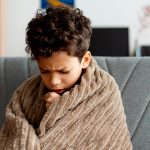 Menino doente sofrendo de gripes e resfriados em casa, com tosse e mal-estar