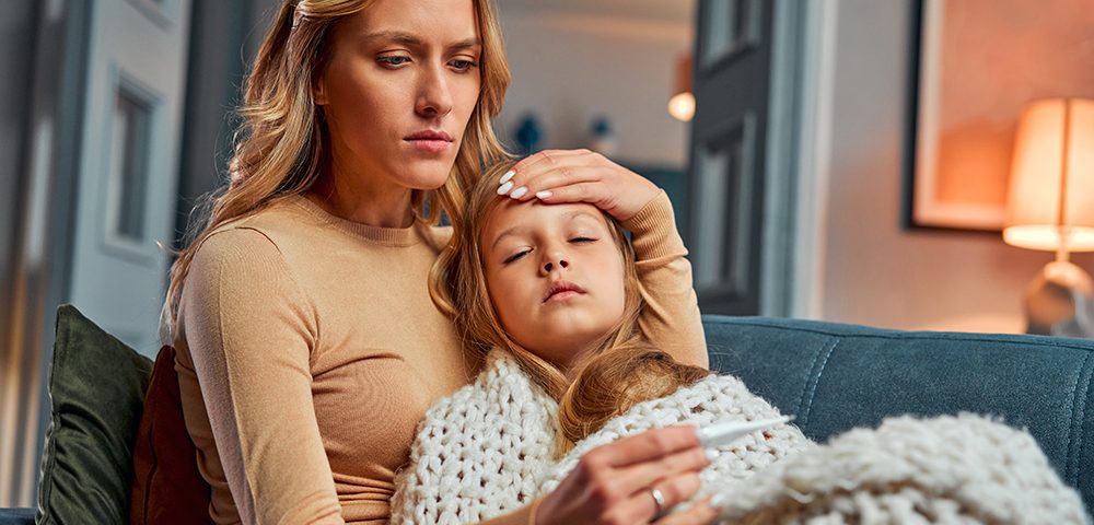 Mãe medindo a temperatura da filha doente.