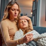 Mãe medindo a temperatura da filha doente.