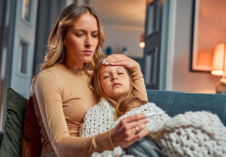 Mãe medindo a temperatura da filha doente.