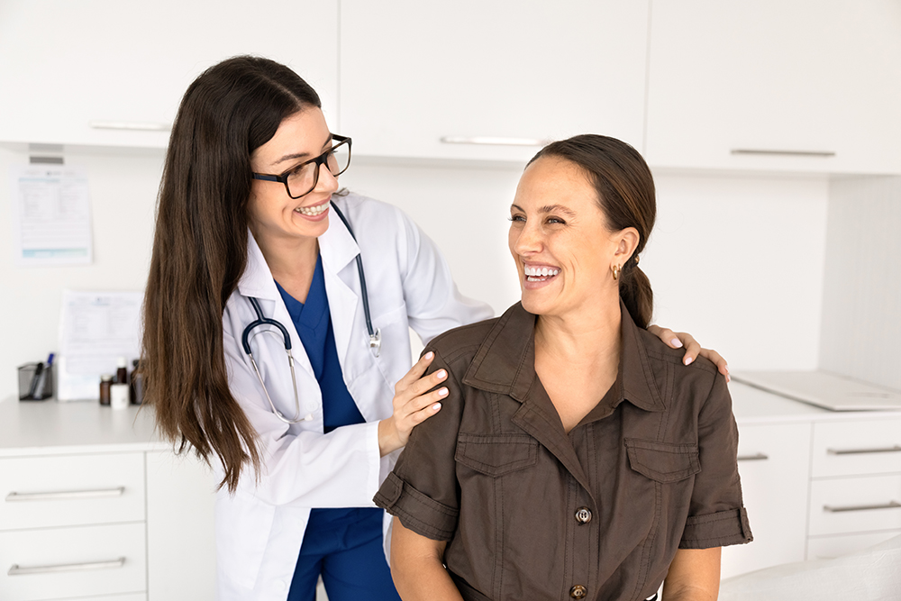 Mulher rindo durante consulta de check-up com a médica no consultório da clínica.